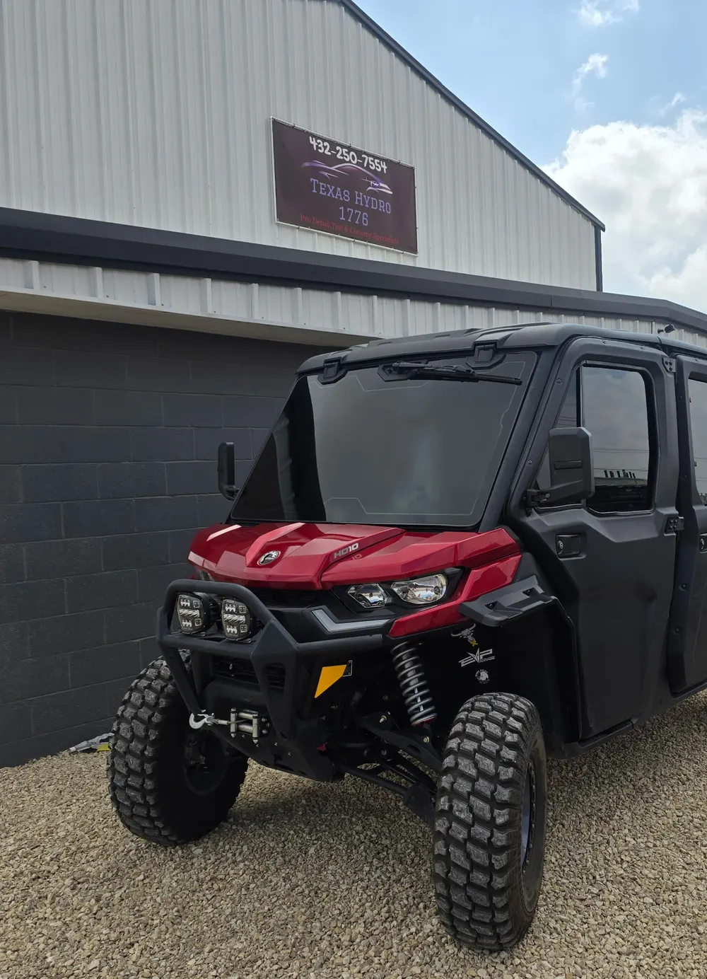 Red Can-Am Defender with tinted cab glass, parked outside the Texas Hydro DNT shop