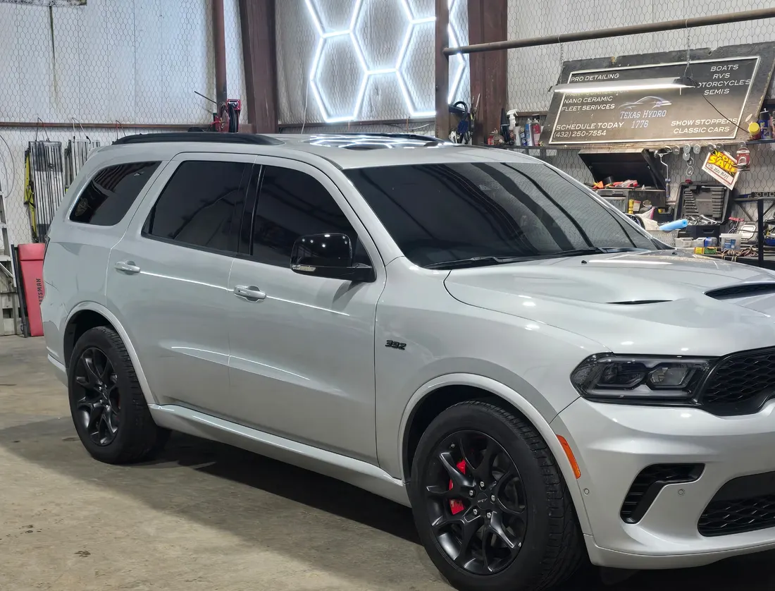 Grey Dodge Durango SRT with dark tinted windows, under the Texas Hydro DNT shop sign