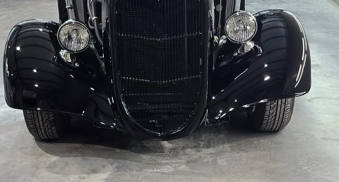Front end of a black 1934 Ford hot rod, chrome headlights and grille