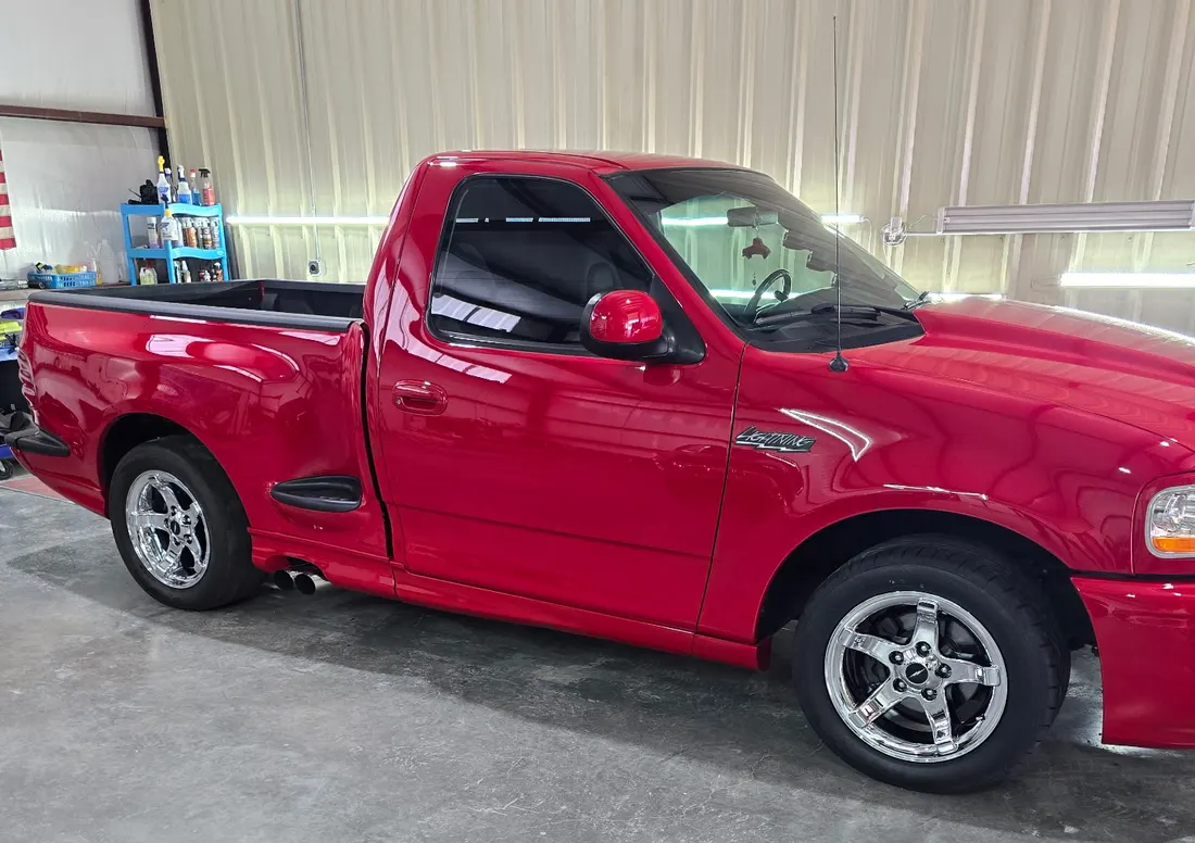 Red Ford SVT Lightning in profile, tinted glass and polished chrome wheels