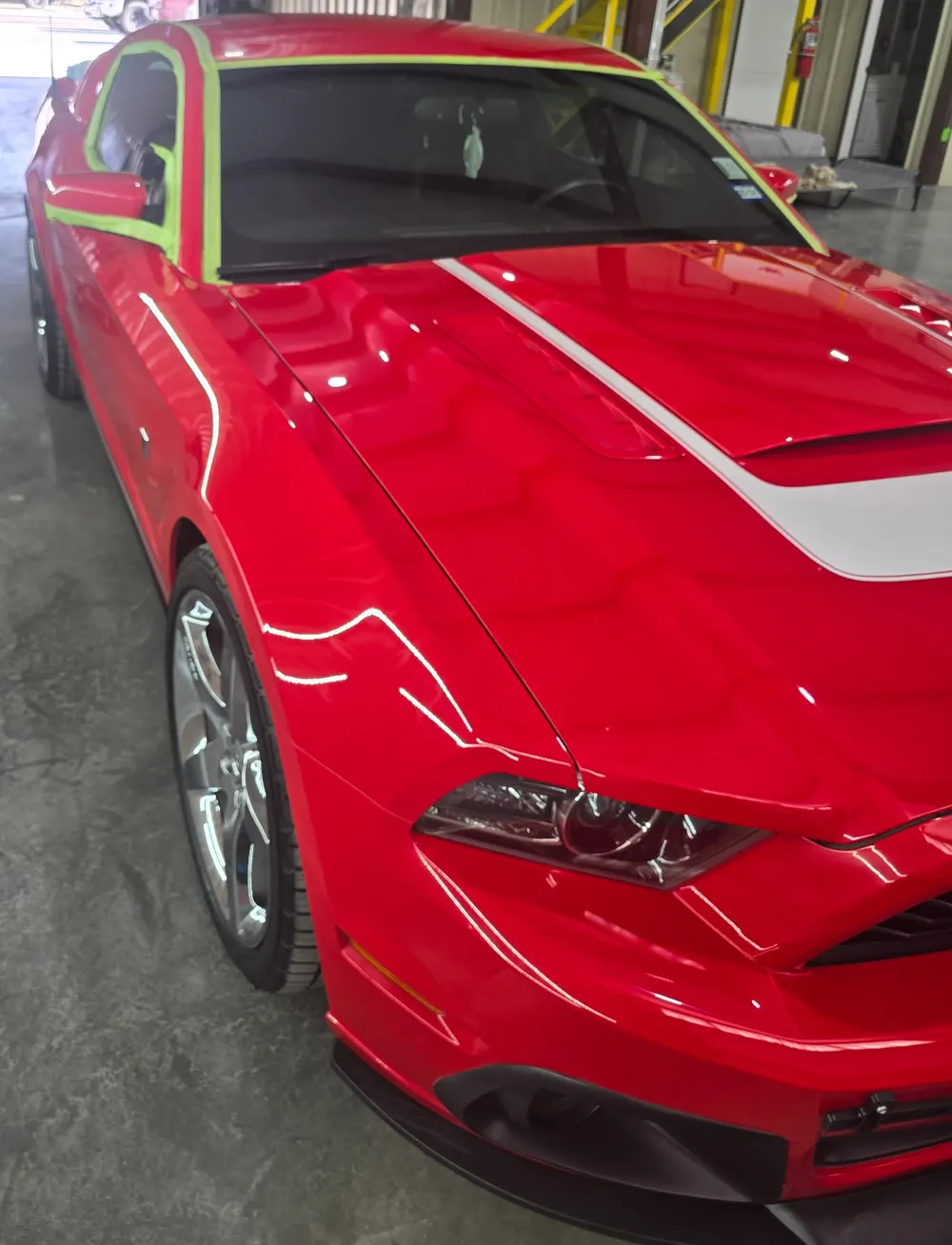 Red Ford Mustang with its glass masked in green tape for a window tint job