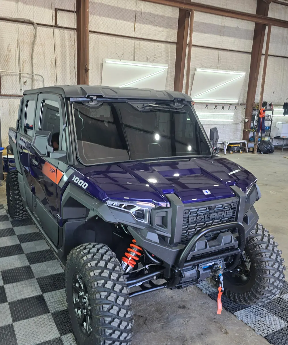 Purple Polaris XP 1000 side by side with tinted cab glass, in the shop bay